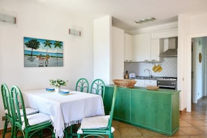 A dining area with a table, chairs, and a painting on the wall. - Dream Villa with Panoramic Terrace near Costa Rei Beach (Costa Rei)