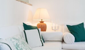 A white sofa with green and white cushions, a table lamp, and a candelabra.