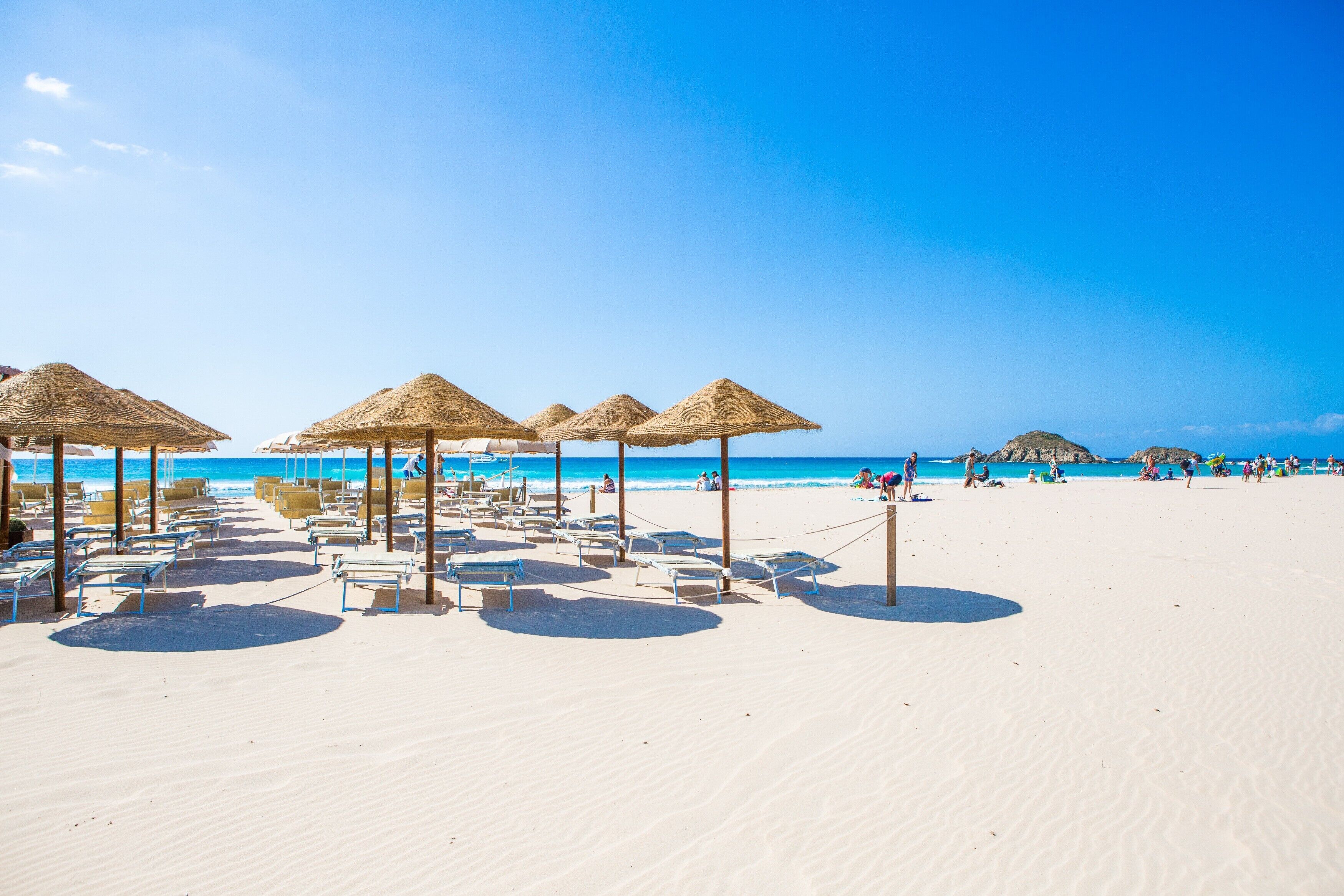 Una spiaggia con lettini e ombrelloni di paglia.