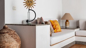 A living room with a white sofa, a lamp, a decorative sun, and a wicker vase. - Villa Roberta at Costa Rei – Sardinian Beach Villa with Garden (Costa Rei)