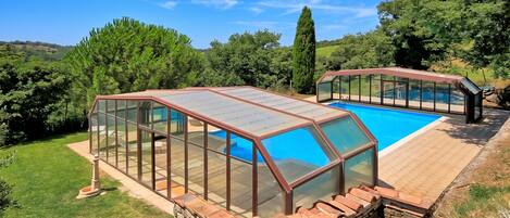 Una piscina con cerramiento de vidrio y pared de piedra.