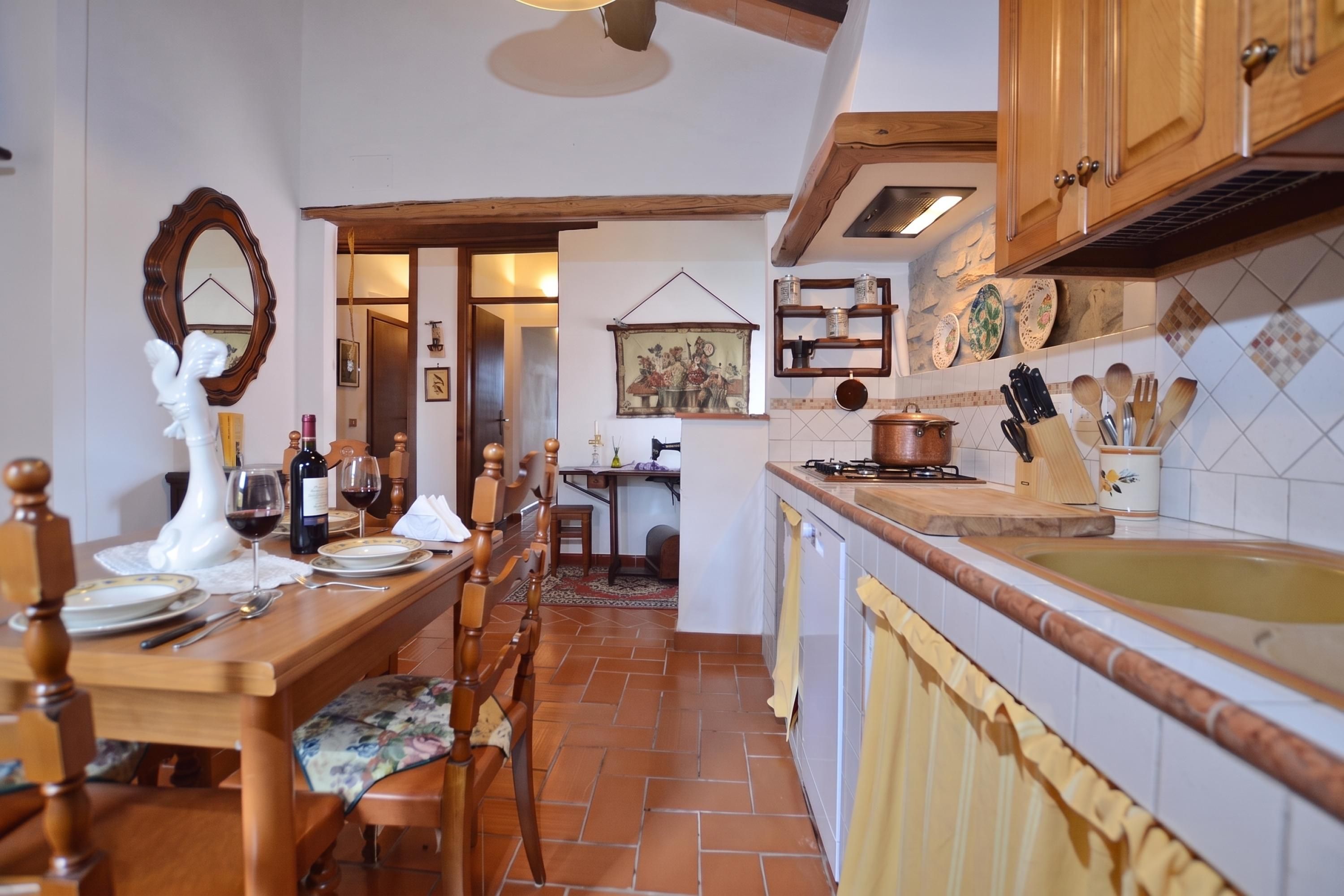 A kitchen with a dining area, wooden cabinets, a tiled backsplash, and a hanging painting.