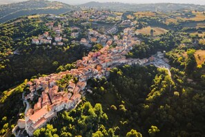 An aerial view of a historic town with a winding street, surrounded by lush greenery and hills. - Casale Mulino (Scansano)