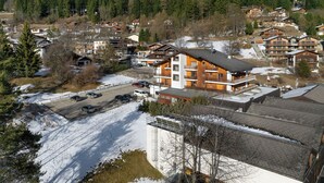 Ein Skigebiet mit mehreren Holzhäusern, einem Parkplatz und einem bewaldeten Berg im Hintergrund.