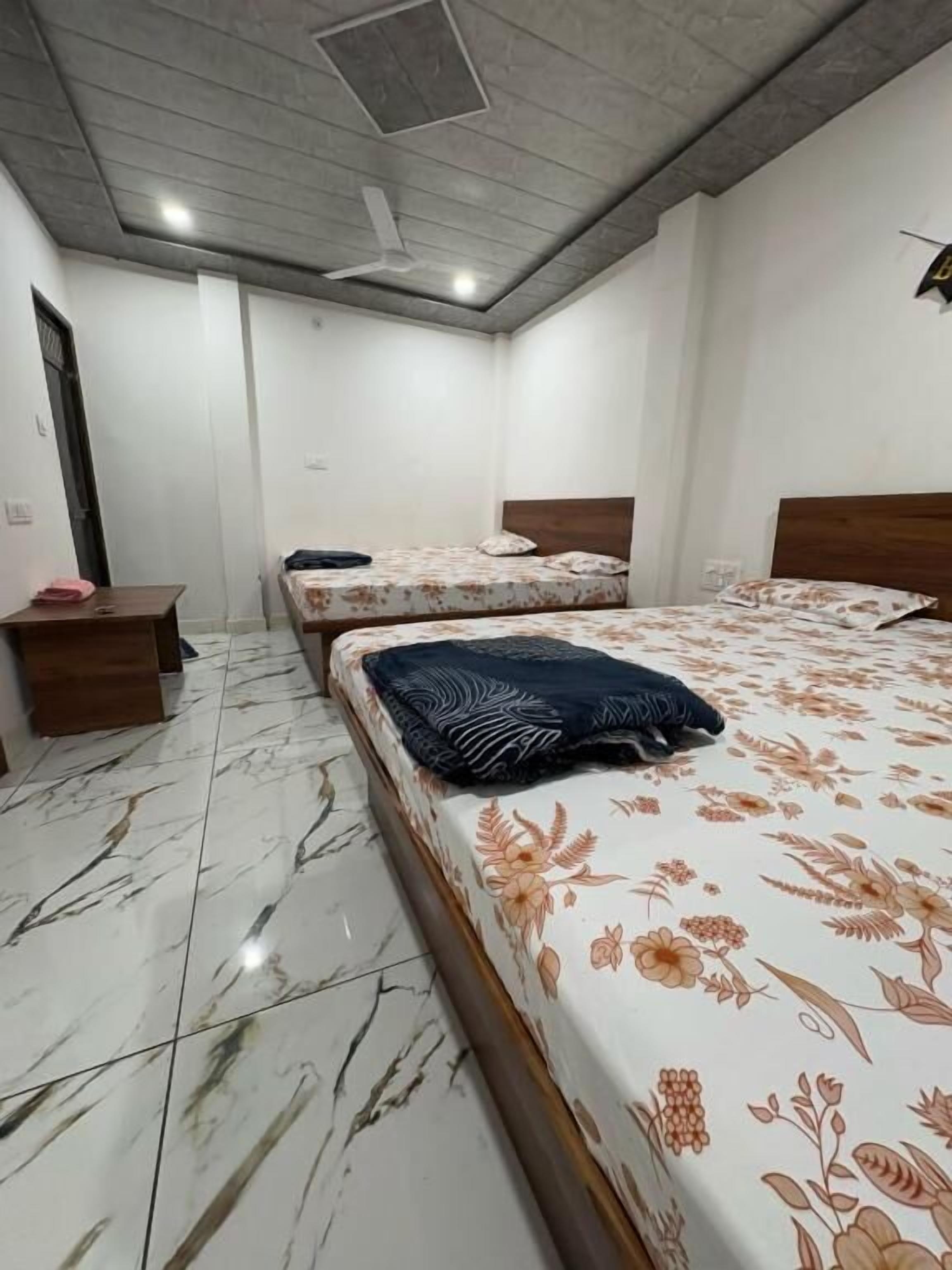 A room with two beds, a wooden headboard, a marble floor, and a ceiling fan.