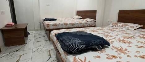 A room with two beds, a wooden headboard, a marble floor, and a ceiling fan.