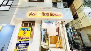 A multi-story hotel with a signboard in a local language, a visible entrance, and a sign indicating availability of AC and non-room accommodations. - Hotel Shree Siddhi vinayak (Ujjain)