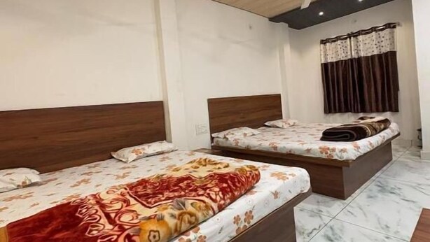 A hotel room with two beds, a ceiling fan, a window with curtains, and a marble floor. - Hotel Shree Siddhi vinayak (Ujjain)