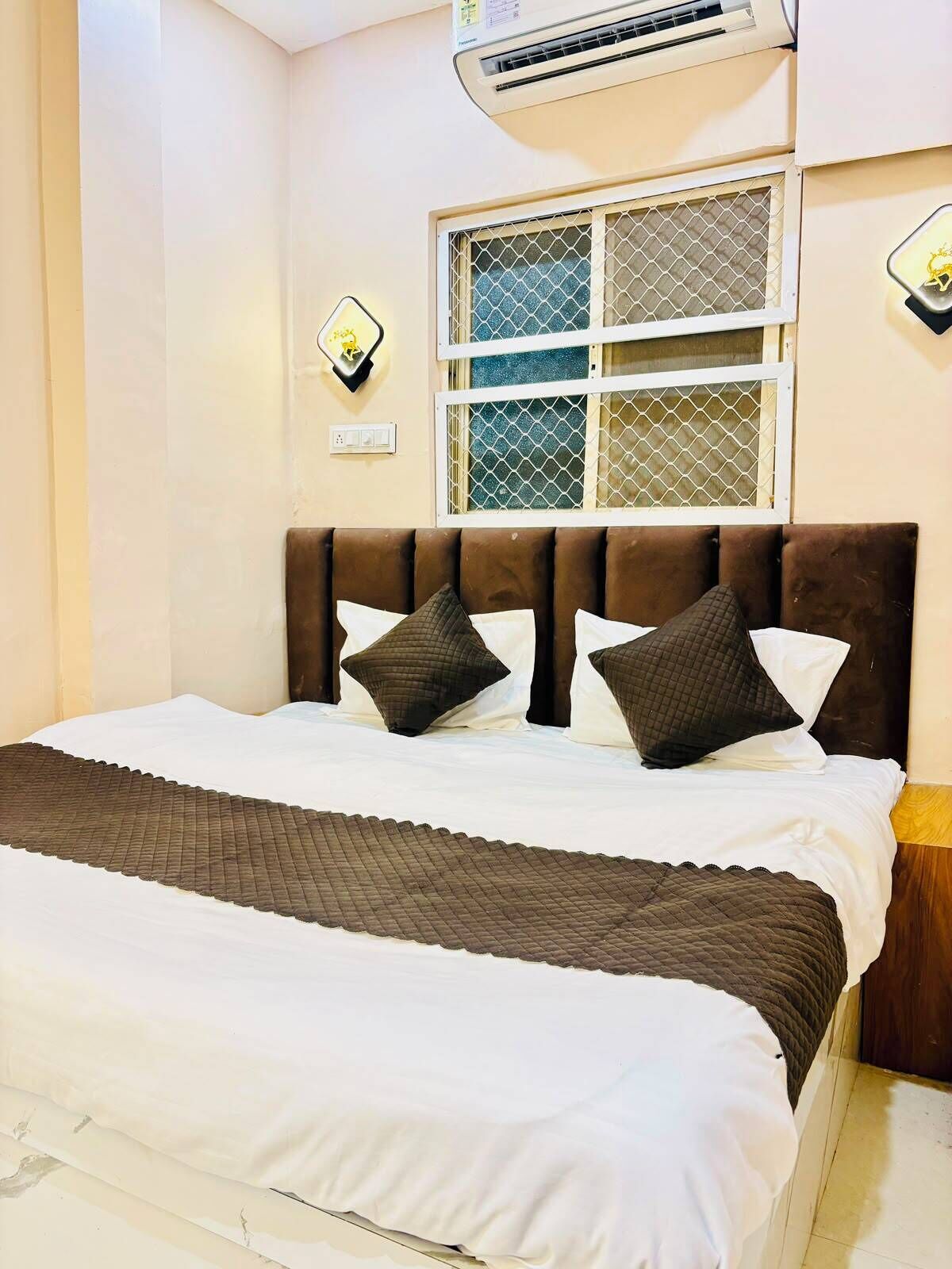 A bedroom with a bed, a window with a metal screen, and an air conditioning unit.