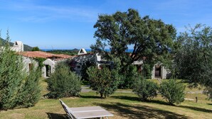 Um pátio com mesa de pingue-pongue, edifícios de pedra e uma árvore grande.