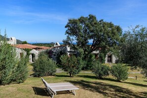 Un patio con mesa de ping pong, edificios de piedra y un gran árbol.