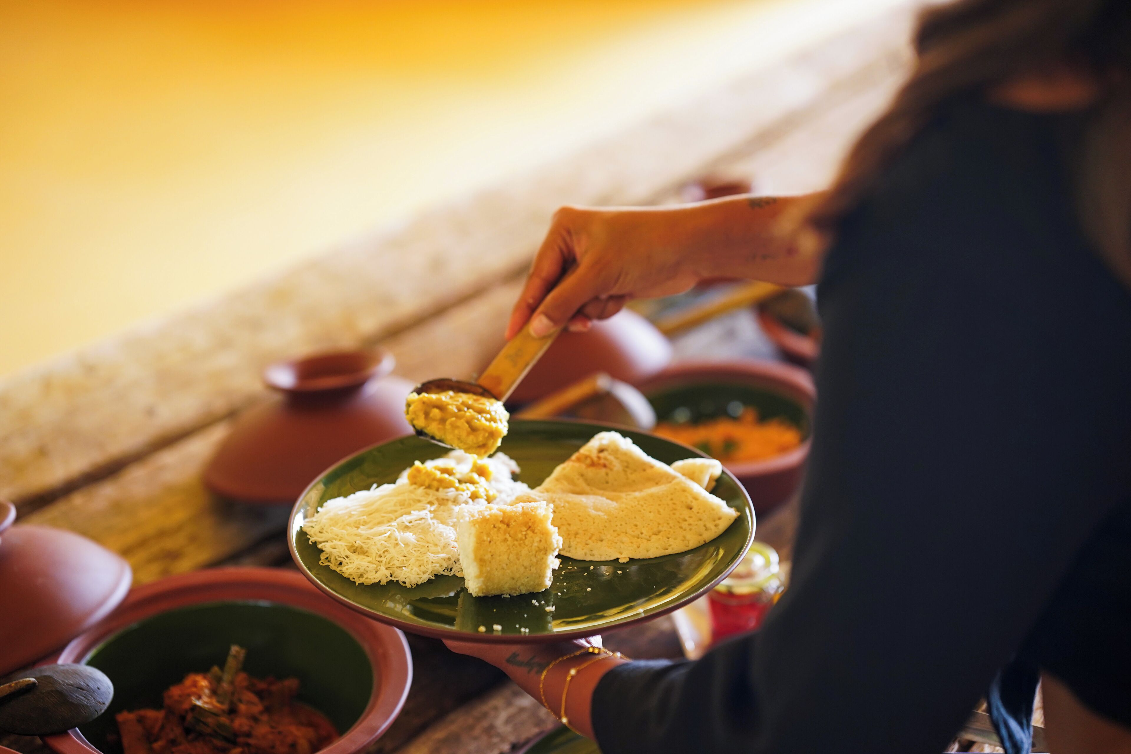 A person serving food from a green plate.