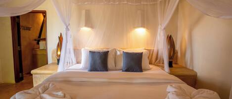 A bed with white linens, two dark pillows, and a canopy.