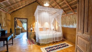 Une chambre à coucher rustique avec un lit à baldaquin, des poutres en bois et un toit de chaume.
