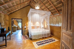 Um quarto rústico com cama de dossel, vigas de madeira e telhado de palha.
