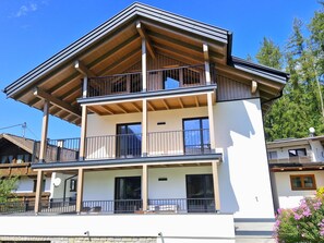 Ein zweigeschossiges Gebäude mit einem Balkon im oberen Geschoss und einer überdachten Terrasse im Erdgeschoss.