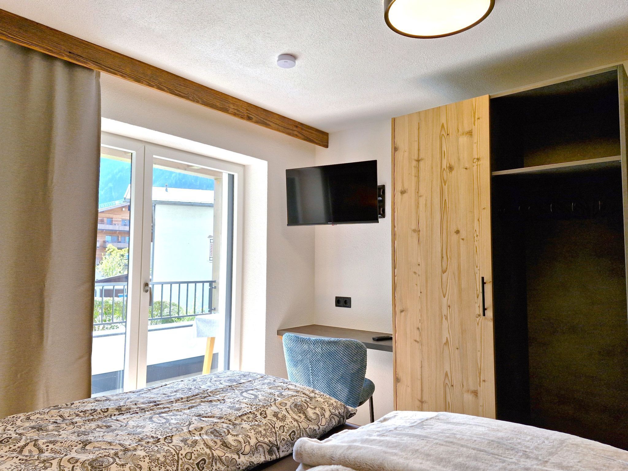 A bedroom with a bed, a desk, a chair, a TV, and a wardrobe.