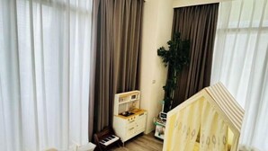 Ein Zimmer mit Klavier, einer kleinen Küchenzeile und einem Spielhäuschen.