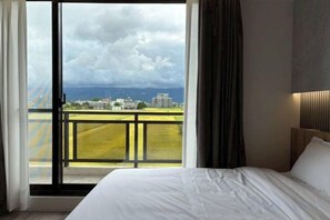 A hotel room with a bed, a view of a cityscape, and a balcony. - NAN SAN VILLA (Yilan)