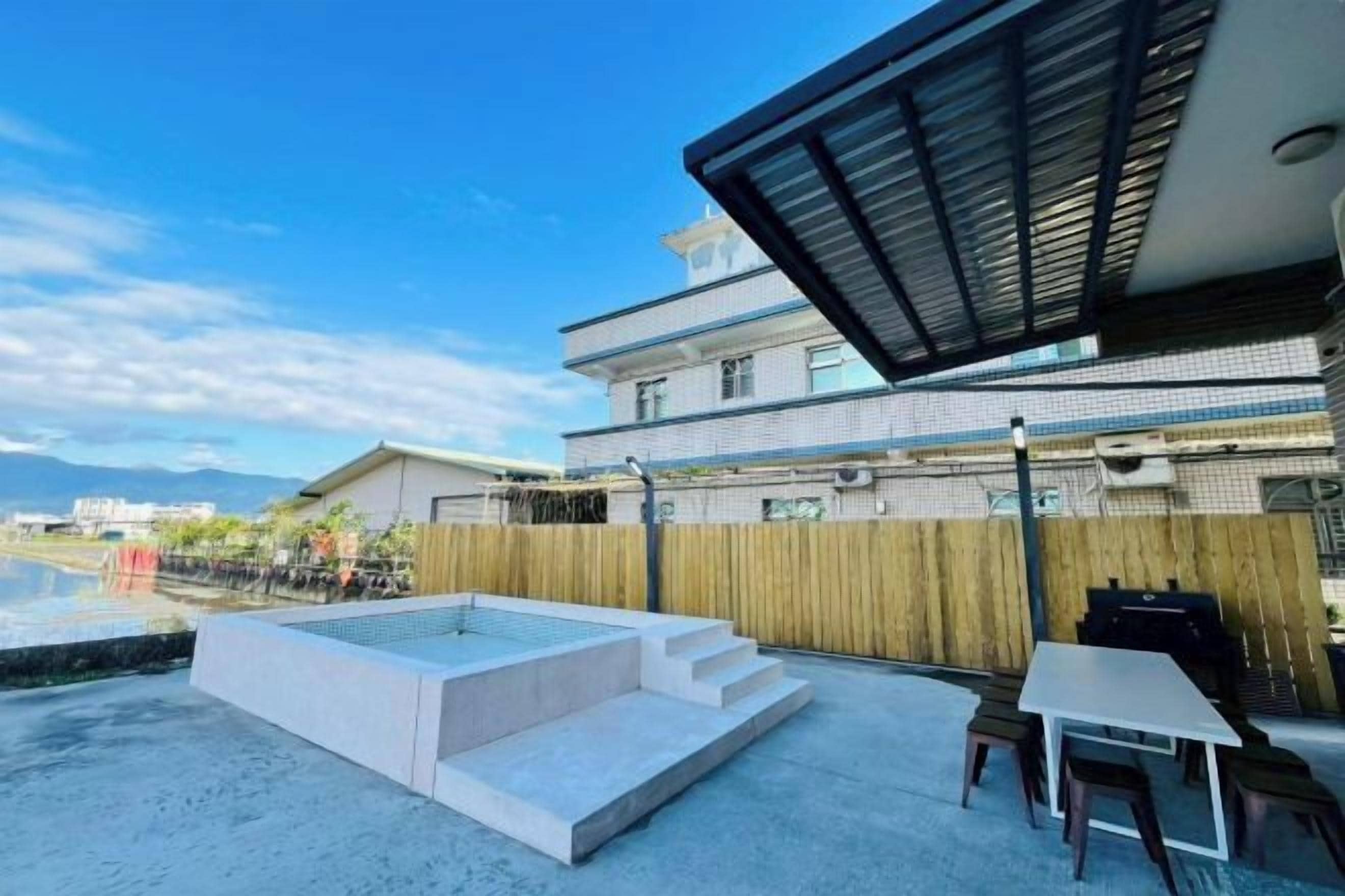 A modern outdoor patio with a hot tub, a table, and chairs.