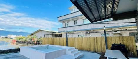 A modern outdoor patio with a hot tub, a table, and chairs.
