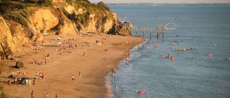 A beach with people swimming and walking along the shore.