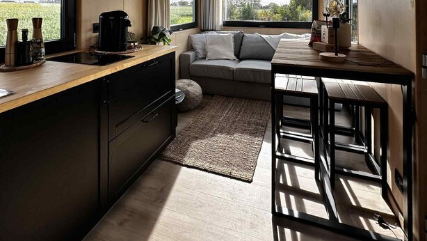 A compact kitchen with a wooden countertop, a built-in stove, and a window overlooking a green landscape.