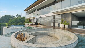 Een modern huis met een groot zwembad, een houten terras en een glazen balkon.