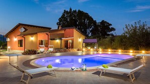 Ein Haus mit Swimmingpool, Liegestühlen und einer Steinmauer.