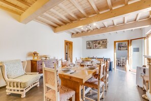 A spacious dining area with a wooden table set for a meal, flanked by chairs with cushioned seats. - Mugello House With Pool (Vicchio)