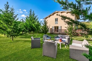 A house with a patio area featuring wicker furniture and a small table. - Mugello House With Pool (Vicchio)