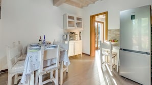A kitchen with a white refrigerator, wooden cabinets, a dining table with chairs, and a microwave. - Mugello House With Pool (Vicchio)