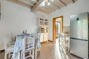 A kitchen with a white refrigerator, wooden cabinets, a dining table with chairs, and a microwave. - Mugello House With Pool (Vicchio)