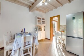 A kitchen with a dining table set for two, a microwave, and a refrigerator. - Mugello House With Pool (Vicchio)