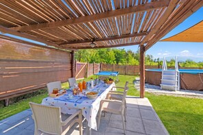 An outdoor patio with a table set for breakfast, surrounded by chairs, and a pool in the background. - Mugello House With Pool (Vicchio)