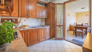 Una cocina con armarios de madera, un lavamanos y una zona de comedor con mesa y sillas.