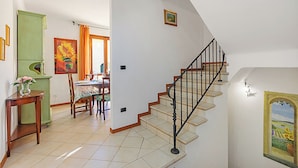 Una escalera que sube a un segundo piso, un comedor con mesa y sillas, y un armario verde.