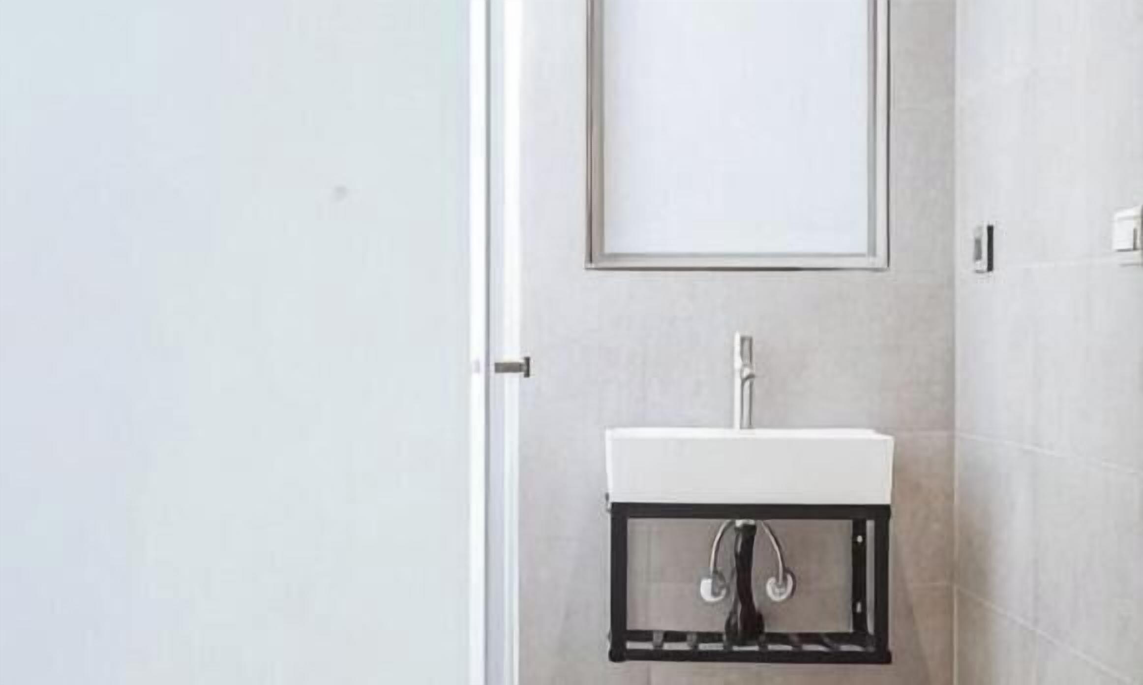 A bathroom with a white sink, a mirror, and a door.