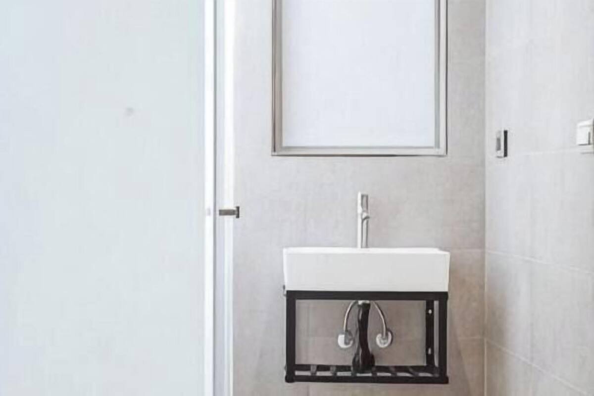 Casa de banho com lavatório branco, espelho e porta.