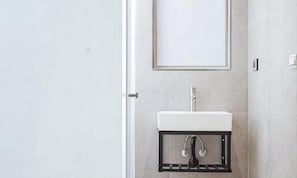 A bathroom with a white sink, a mirror, and a door. - White Space Design Hotel (Taipei)