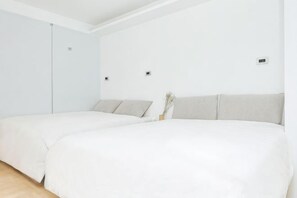 Ein Zimmer mit zwei Betten, einem Schrank und einer kleinen Vase mit Blumen.