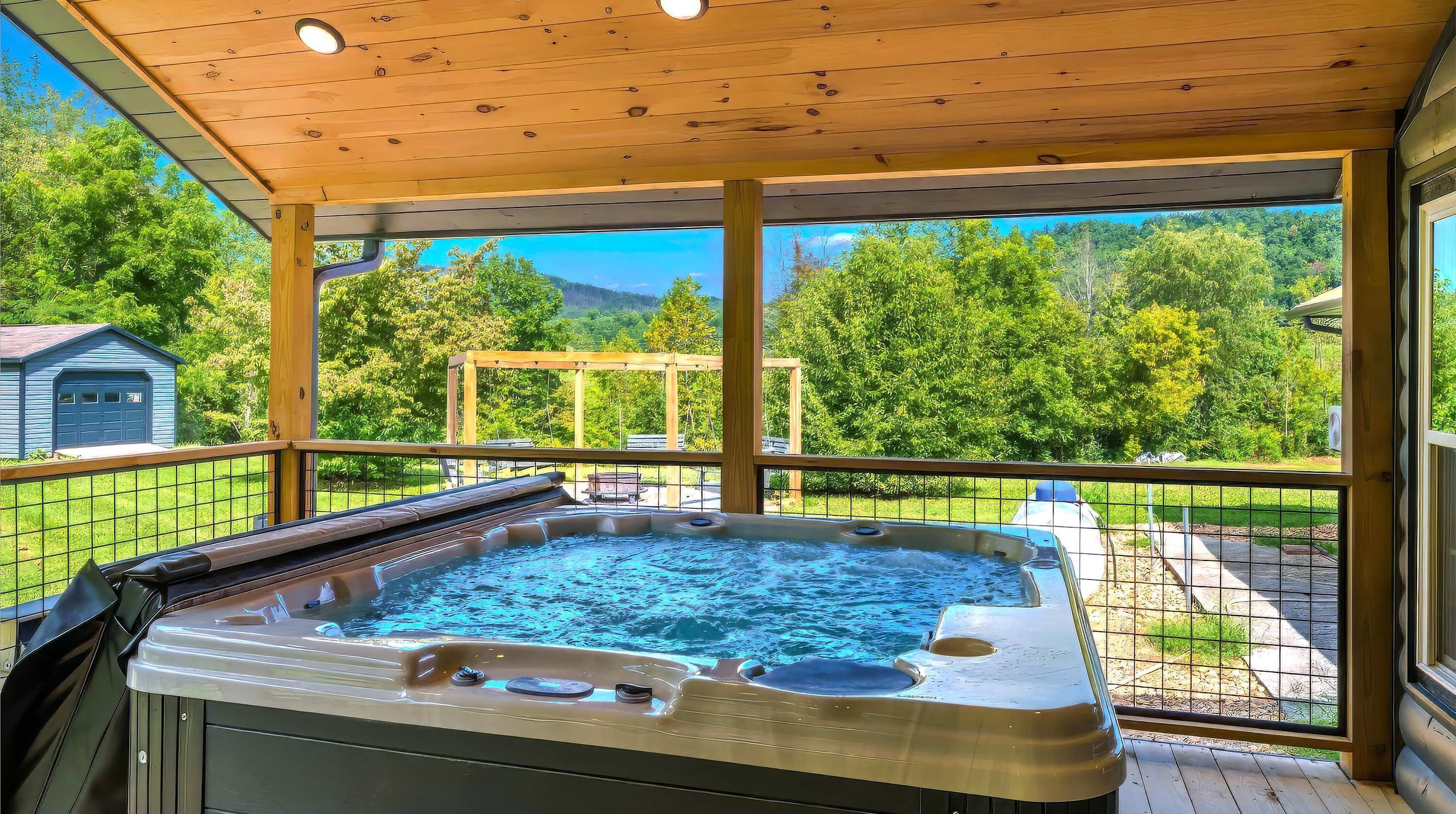 Jacuzzi bajo una terraza de madera con vistas a un paisaje verde.