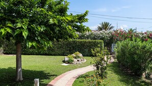 Ein Garten mit gepflastertem Weg, üppiger Vegetation und blühenden Pflanzen.
