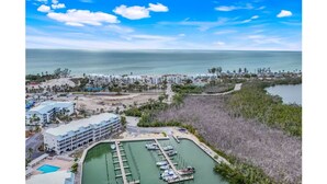 An aerial view of a coastal resort with a marina, a swimming pool, and beachfront accommodations. - Charming bayside condo in south seas resort Captiva for a relaxing getaway (Captiva)