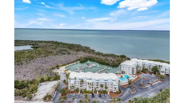 An aerial view of a resort with a marina, swimming pool, and beachfront accommodations. - Charming bayside condo in south seas resort Captiva for a relaxing getaway (Captiva)