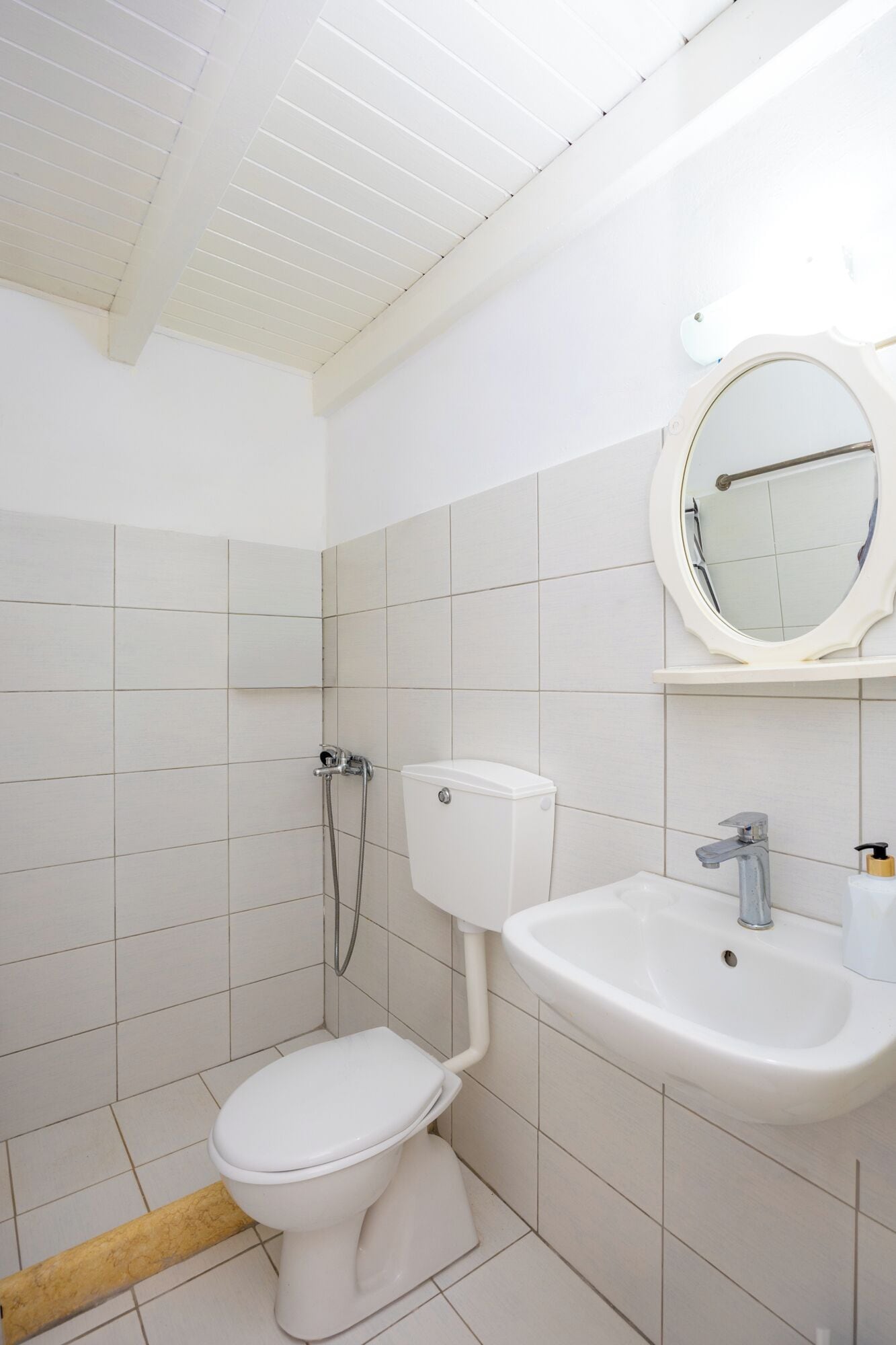 Et badeværelse med toilet, håndvask og brusebad.