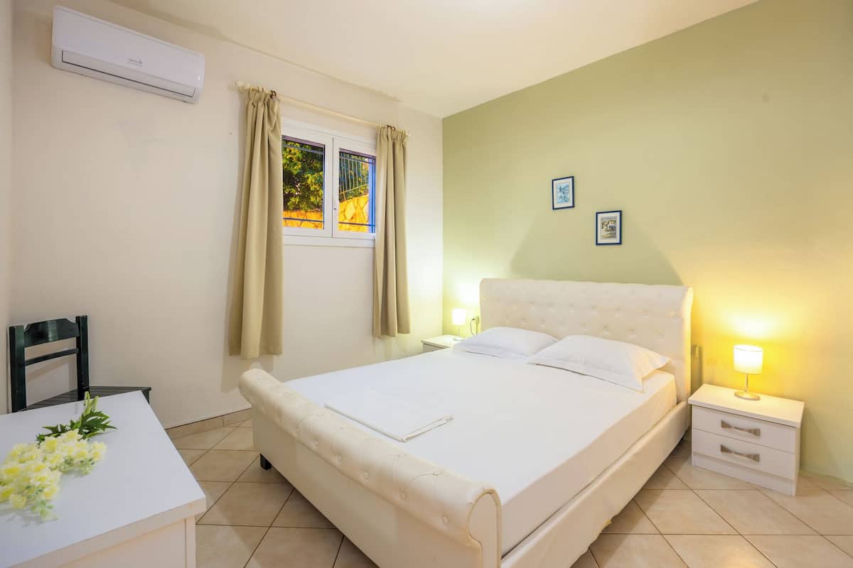 A bedroom with a bed, bedside tables, a chair, and a window with curtains.