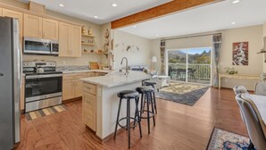 A modern kitchen with a central island, bar stools, and a dining area with a view of the outdoors. - Lakeview Home steps away Twin Rocks Beach Access (Rockaway Beach)