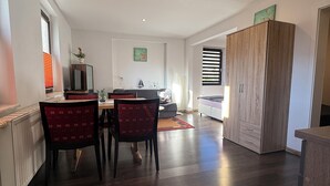 Un vaste espace de vie comprenant une table et des chaises, un grand meuble en bois et une vue sur la pièce adjacente.