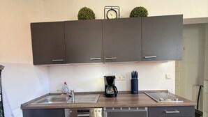 Une cuisine moderne avec des meubles de couleur sombre, un lave-vaisselle, une machine à café et un évier.